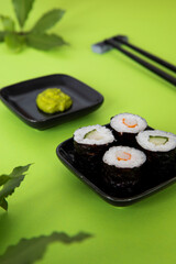 Sushi hosomaki maki set with wasabi paste in vibrant green color background.