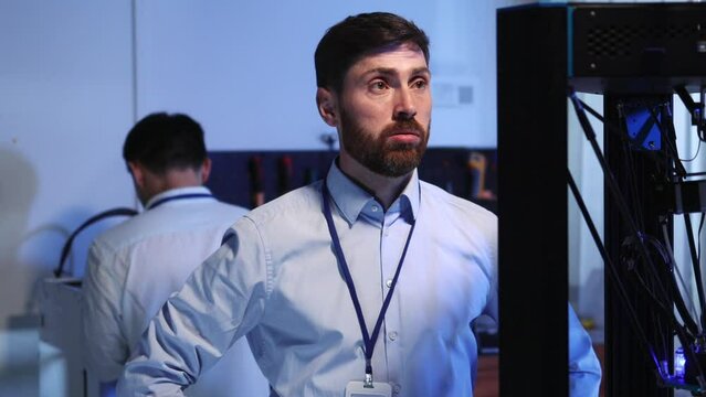 Young adult technical specialist looking on 3d printer thinking for solution. Couple multi-ethnic coworkers repairing printing machine celebrating success.