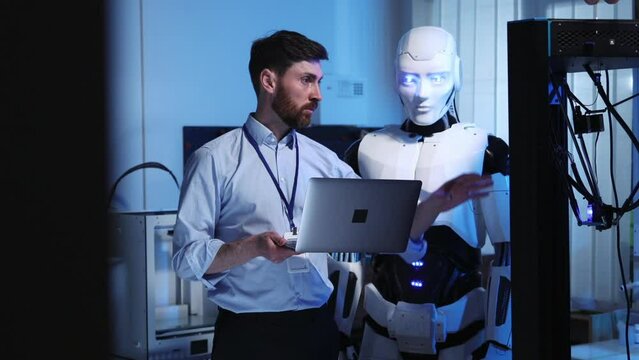 Future is now. Professional lab worker scientist explaining electronics work to cybernetic AI robot employee cooperating on 3d printer machine. Technologies.