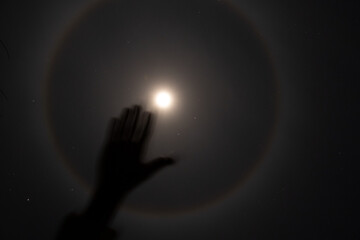 The halo phenomenon on the moon over Ukraine at night and the girl's hand , the night moon and...