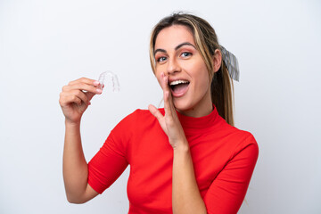 Young caucasian woman holding invisible braces on white background whispering something
