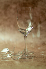 Two broken wine glasses on a light sand background