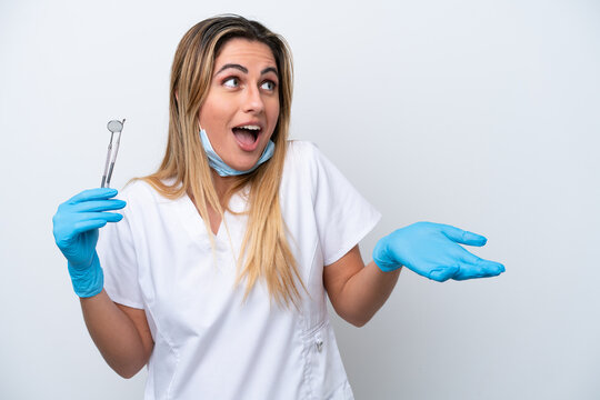 Dentist woman holding tools isolated on white background with surprise expression while looking side