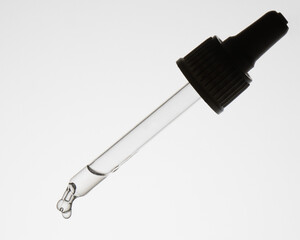 transparent pipette with a clear liquid with a black cap on a white background. Side view, close up, macro photo