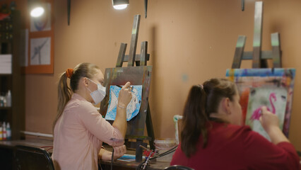 Woman artist learns to paint with airbrush with acrylic dye, paper and easel. Indoors. Concept...