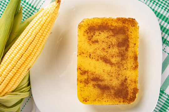 Brazilian Cural, candy corn and corn arranged on a table with a green and white tablecloth, dark background, top view.