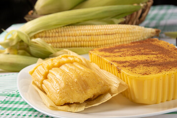 Brazilian Cural, candy corn and pamonha, corn on the cob arranged on a table with a green and white tablecloth, dark background, selective focus.