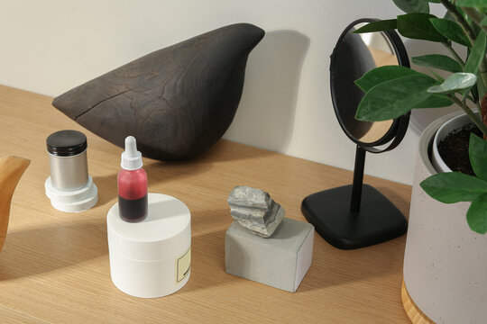 different cosmetics products, cream and serum, moisturiser and exfoliating acid are on the makeup table, small mirror, green plant in concrete pot, stylish design of beauty treatment products