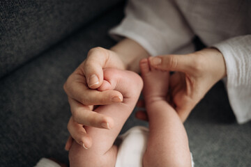 om holds the baby's legs in her hands, warm affection and care