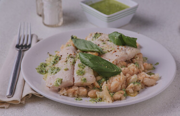 Fish fillets with white bean mash,garnished with pesto sauce.