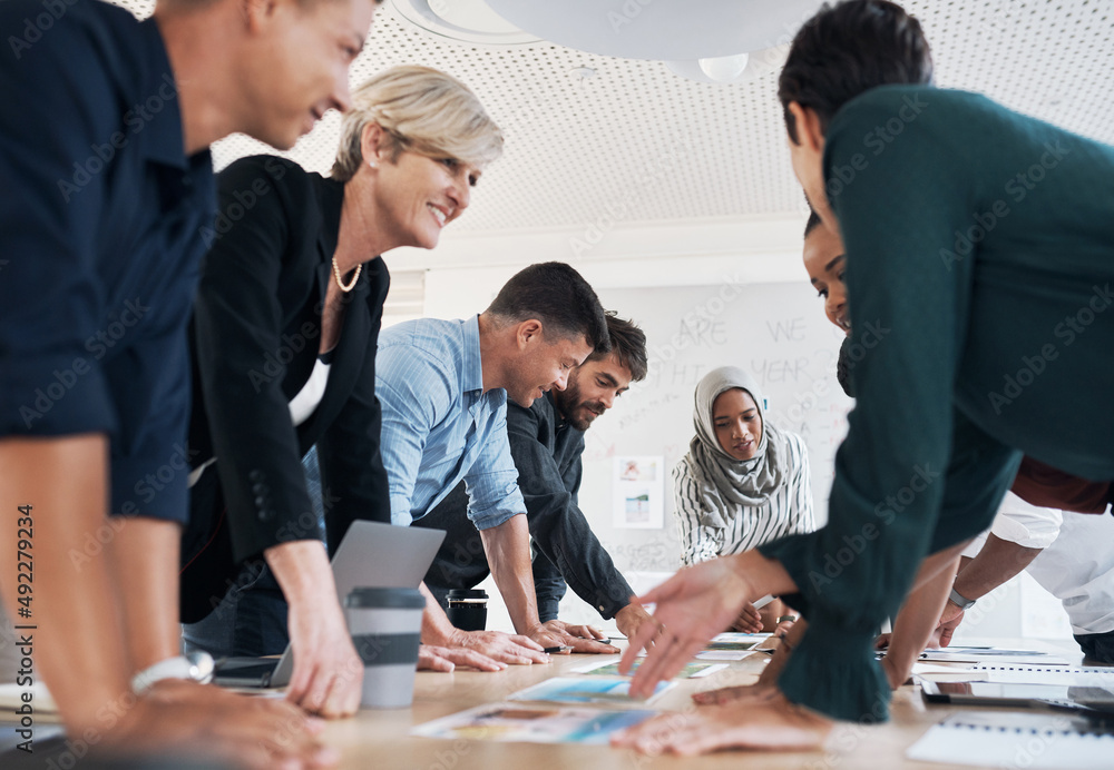 Poster all the input they need to make it work. shot of a group of businesspeople discussing paperwork duri