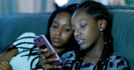 Two girl looking at cellphone at night. Black African ethnicity