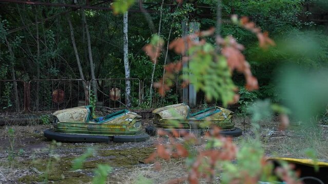 Abandoned autodrome in Pripyat in Chernobyl zone. Metal rusty cars of the Soviet attraction. High quality 4k footage