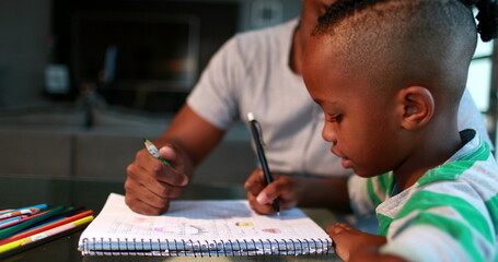 Little boy studying at home doing homework with father help