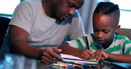 Little boy doing homework at home, African father helping son with study