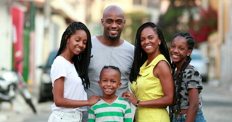 Happy African family portrait standing for photo outside. Cheerful black parents and children