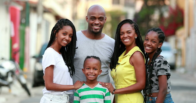 Happy African family portrait standing for photo outside. Cheerful black parents and children