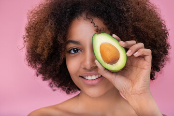 Portrait of a beautiful young dark skinned woman with curly hair covers one eye with half an...