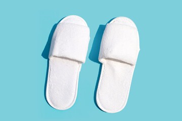 Hotel slippers on blue background. Copy space