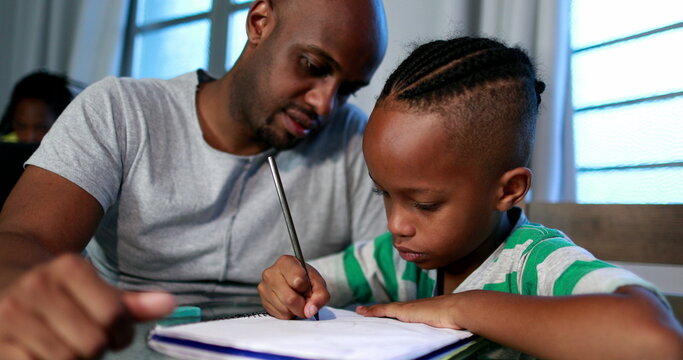 Father helping son with homework at home. African black dad mentoring little boy