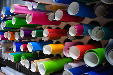 A rack with rolls of self-adhesive film for advertising. Vinyl film on the stand in the store.Advertising production.