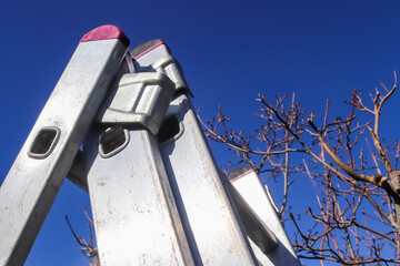 The top of an aluminum ladder against blue sky.