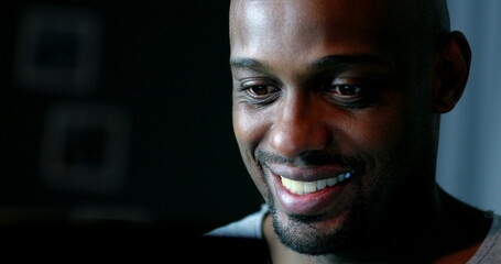 Close-up black man face looking at computer screen at night