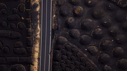 Bycicle rider training and enjoying on a long straight road inscenic volcanic place. Above drone...