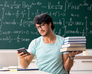 Young male student mathematician in front of chalkboard