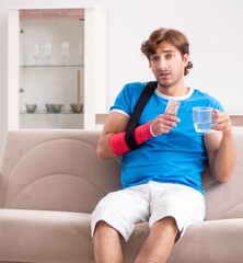 Fototapeta na wymiar Young man with injured arm sitting on the sofa