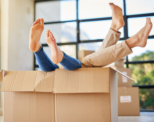 Handle with care. Shot of an unidentifiable young couple lying in a box together with their feet...