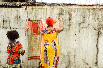 Woman hanging washed clothes with her daughter.