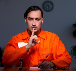 Young convict man sitting in dark room