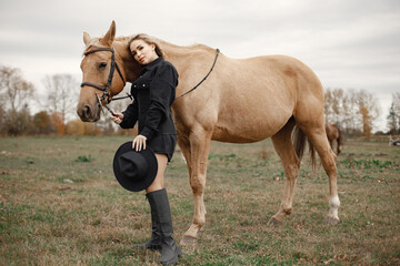 Beautiful blonde woman with blonde hair and a brown horse in the field