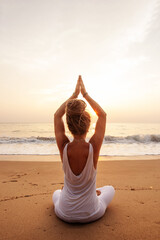 Fototapeta na wymiar Woman practicing yoga by the ocean at dawn