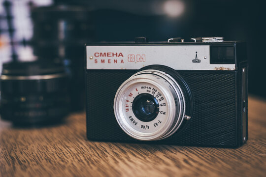 Old vintage Russian film camera on wooden table. Model Lomo Smena 8, front view, close up, vibrant tone.