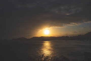 Fototapeta premium The sun shines on the sea just before sunset under the white clouds