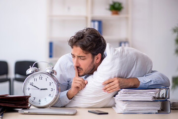 Young male employee in oversleeping concept