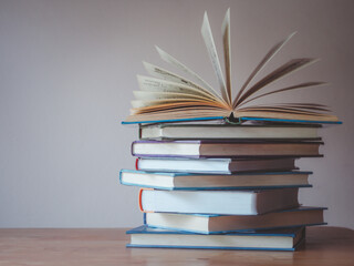 A simple composition of many books, stack or pile of books on wooden table, one of them open with copy space.