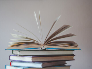 A simple composition of many books, stack or pile of books on wooden table, one of them open with copy space.