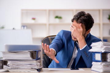 Young male employee and too much work in the office