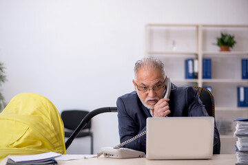 Old male employee looking after new born at workplace