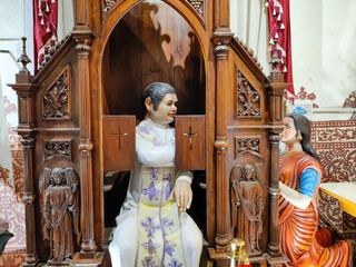 GOA, INDIA - 13 Jan 2022 Statue of priest sitting behind the grid and listening the confession in...