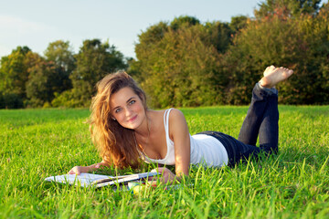 Beautiful уoung woman reeding on a green meadow