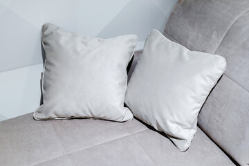 Fragment of a gray sofa with square cushions. Close-up