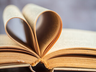 The heart shape created by the open yellowed pages of an old hardcover book, soft focus, shallow depth of field.  I love reading! Educational topics. No people