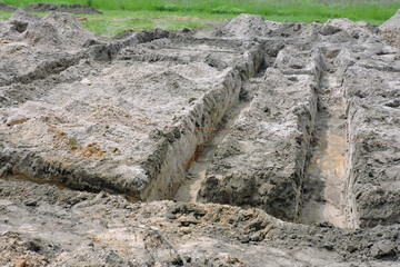 The deep excavation made for pouring concrete footing for a new house, two batter-boards and a red...
