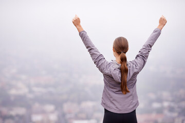 Feeling on top of the world in the morning. Rearview shot of a woman training outdoors with her arms outstretched.