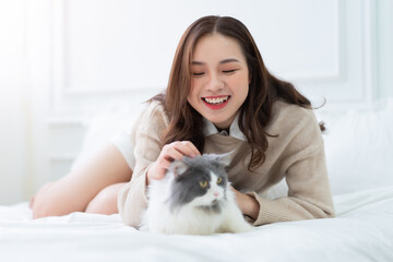 Young Asian woman playing with cat at home