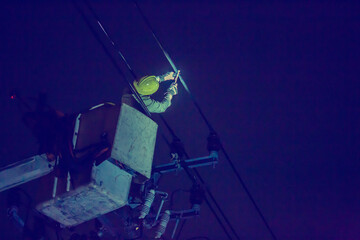 Selective focus to electrical worker is connecting high-voltage cable  with a crane at night. Dark...